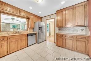 kitchen featuring a sink, backsplash, appliances with stainless steel finishes, and light countertops