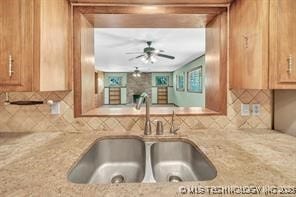 kitchen featuring light stone countertops, backsplash, and a sink