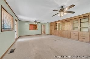 unfurnished living room with a ceiling fan, visible vents, and baseboards