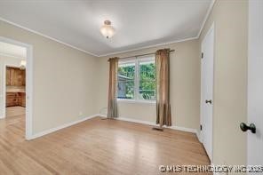 unfurnished room featuring wood finished floors, baseboards, and ornamental molding