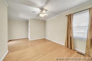 spare room featuring ornamental molding, baseboards, ceiling fan, and wood finished floors