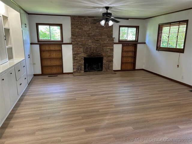 4331 S Norfolk Ave, Tulsa, OK 74105 - unfurnished living room featuring light wood-type flooring, a ceiling fan, a stone fireplace, baseboards, and crown molding