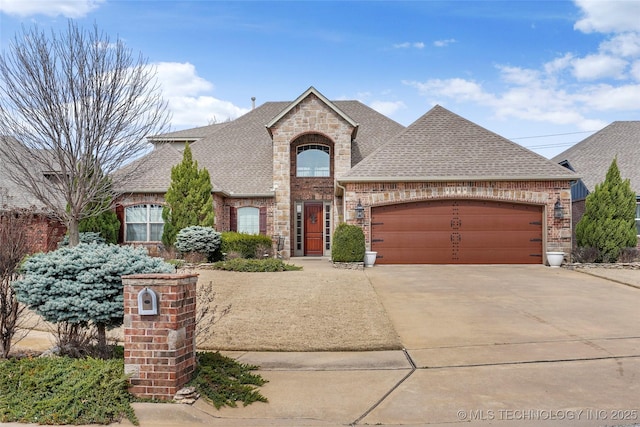 french country inspired facade with concrete driveway, a garage, brick siding, and roof with shingles