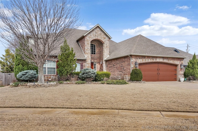 french country inspired facade with concrete driveway, brick siding, a garage, and a shingled roof