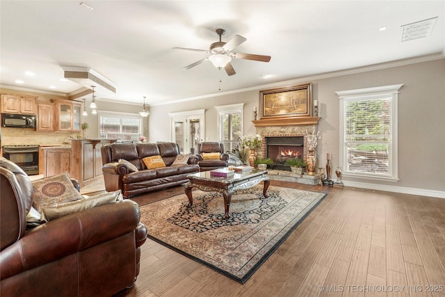 living room with a wealth of natural light, a warm lit fireplace, and wood finished floors