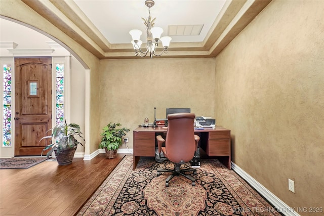 office space with visible vents, baseboards, a chandelier, wood finished floors, and arched walkways