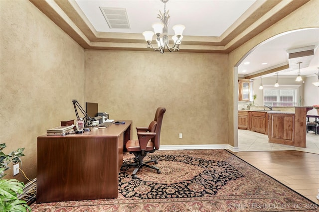 office featuring visible vents, a chandelier, light wood-style flooring, arched walkways, and a sink