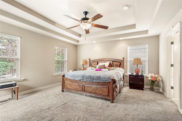 bedroom featuring a tray ceiling, light colored carpet, and baseboards