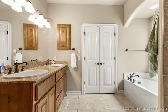 bathroom featuring tile patterned floors, a bath, double vanity, and a sink