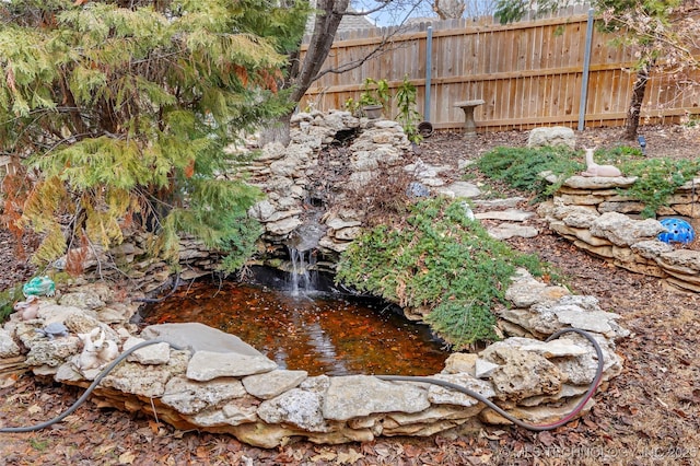 view of yard with a small pond and fence