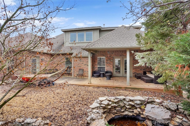 back of property with brick siding, a patio, and roof with shingles