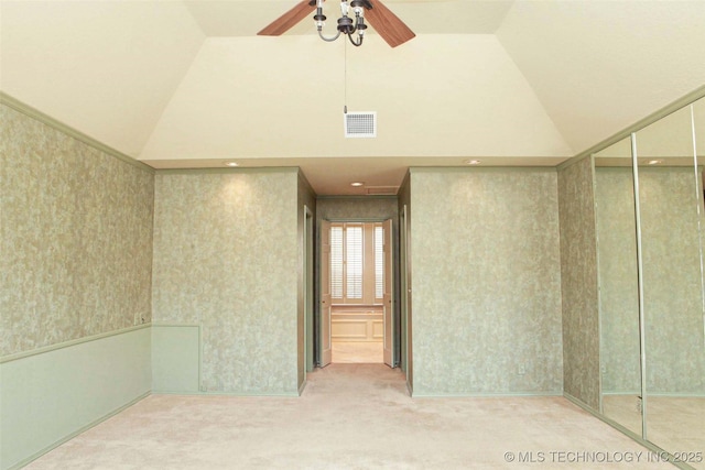 carpeted empty room featuring wallpapered walls, ceiling fan, visible vents, and high vaulted ceiling