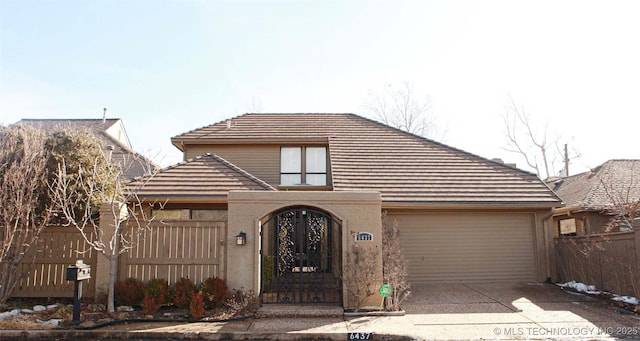 view of front of home with concrete driveway, an attached garage, fence, and stucco siding