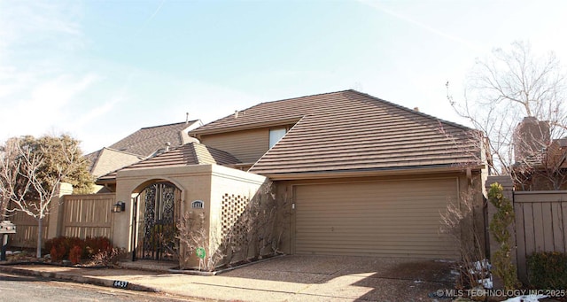 view of front of home with a gate, concrete driveway, an attached garage, and fence