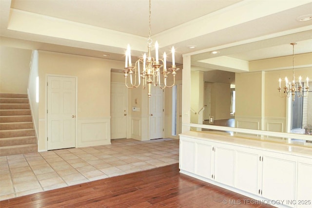 unfurnished dining area with a raised ceiling, a notable chandelier, and a decorative wall