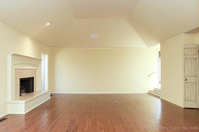 unfurnished living room featuring lofted ceiling, a fireplace with raised hearth, crown molding, and hardwood / wood-style flooring