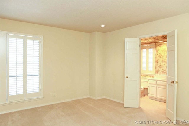 unfurnished room with baseboards and light carpet