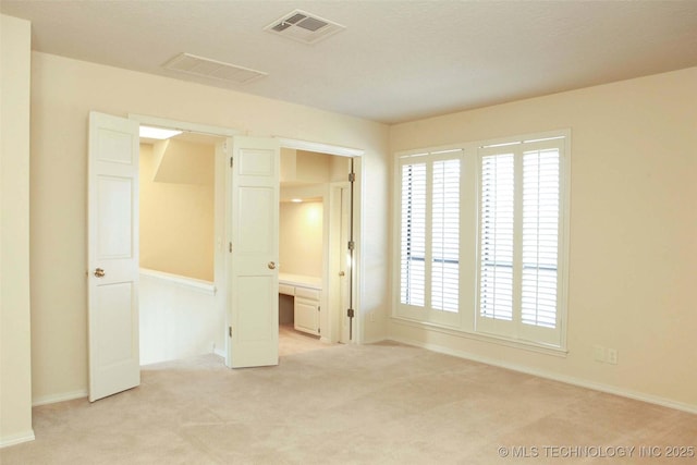 spare room featuring light carpet and visible vents