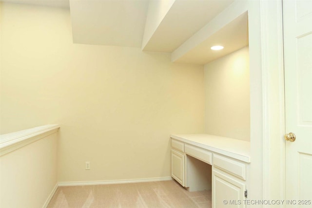 unfurnished office featuring recessed lighting, light colored carpet, built in desk, and baseboards