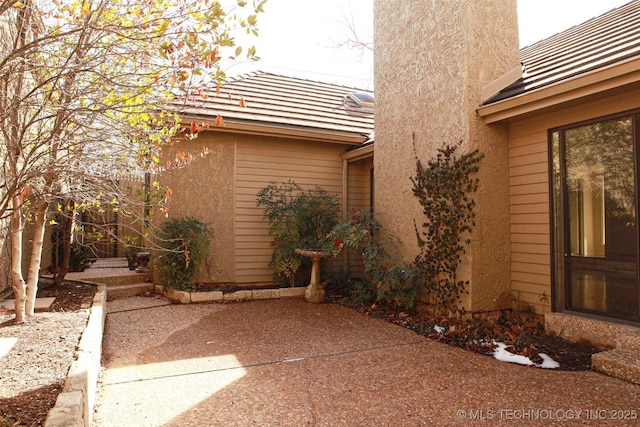 view of property exterior featuring stucco siding, a patio, and a tile roof