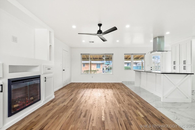 unfurnished living room featuring a ceiling fan, visible vents, recessed lighting, a glass covered fireplace, and marble finish floor