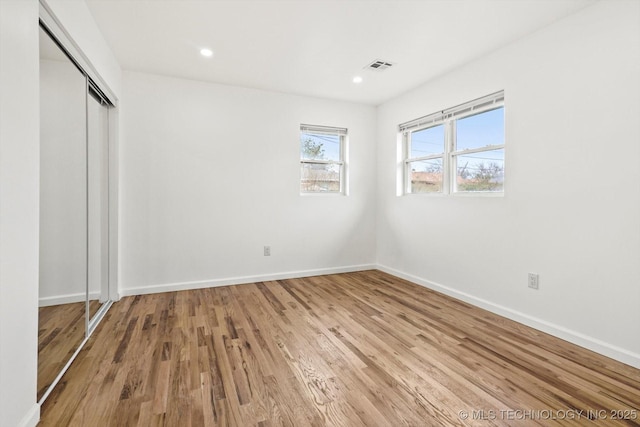 unfurnished bedroom featuring baseboards, visible vents, recessed lighting, a closet, and light wood-type flooring