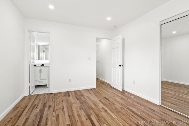 unfurnished bedroom featuring recessed lighting, wood finished floors, baseboards, and a sink