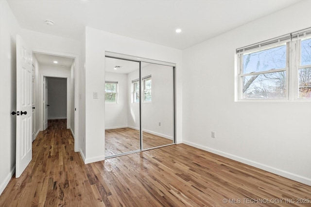 unfurnished bedroom featuring recessed lighting, a closet, baseboards, and wood finished floors