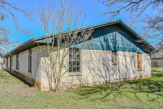 view of side of home featuring a yard and brick siding