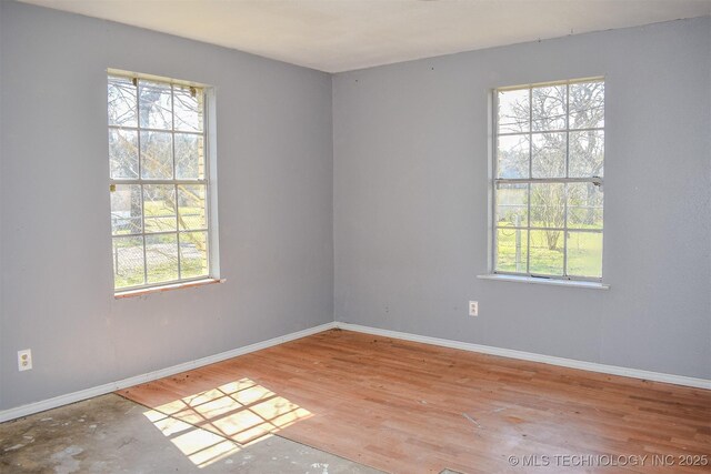 empty room with baseboards, plenty of natural light, and wood finished floors