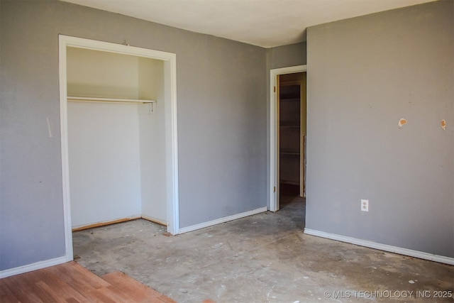 unfurnished bedroom featuring a closet, concrete flooring, and baseboards