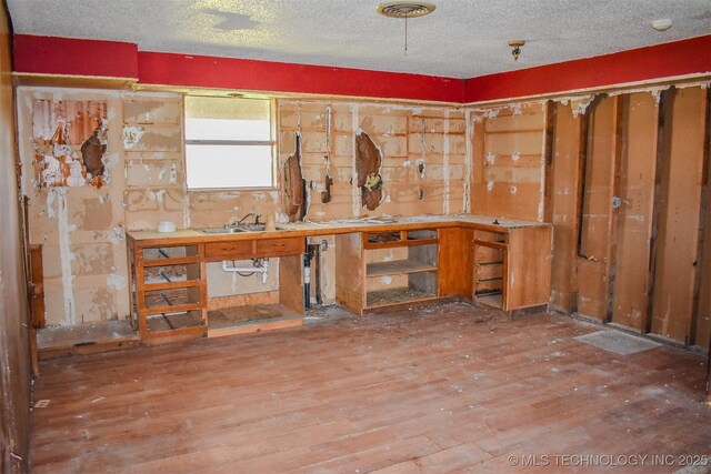 interior space with visible vents, a sink, a textured ceiling, wood finished floors, and a workshop area