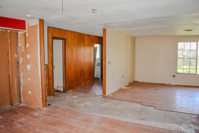 unfurnished room featuring a textured ceiling and wood walls