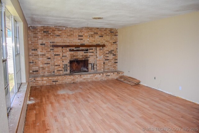 unfurnished living room with wood finished floors, a fireplace, and a textured ceiling