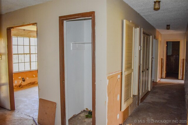 hallway featuring unfinished concrete floors and a textured ceiling