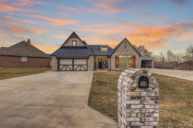 view of front facade with a standing seam roof, stone siding, board and batten siding, and driveway