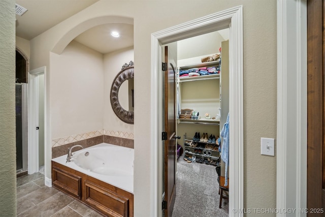 bathroom with visible vents, a garden tub, a stall shower, and a spacious closet