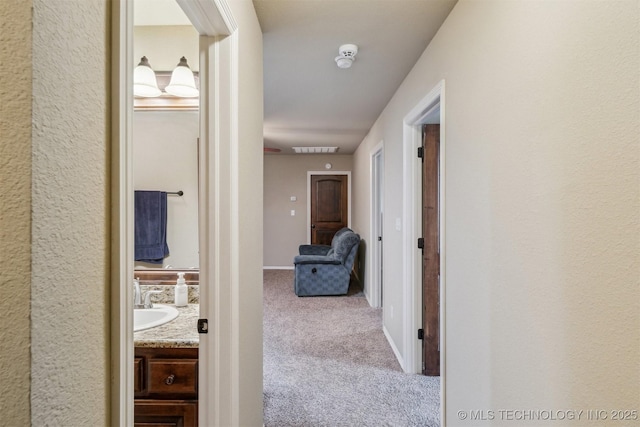 corridor with a sink, baseboards, and carpet