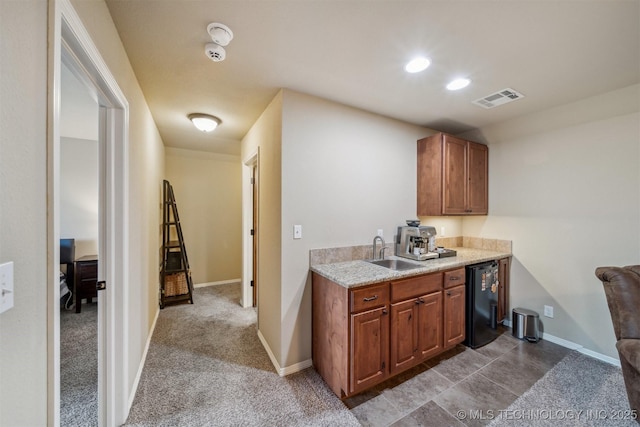 kitchen with baseboards, visible vents, a sink, light countertops, and dark carpet