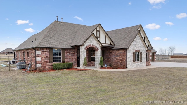 view of front of house featuring brick siding, a shingled roof, a front lawn, central AC unit, and stone siding