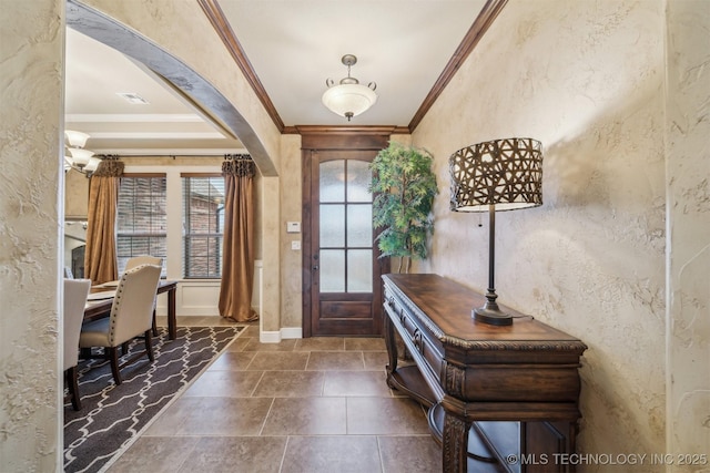 foyer featuring baseboards, visible vents, arched walkways, ornamental molding, and a textured wall