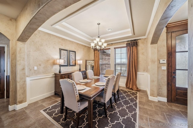 dining area featuring a chandelier, visible vents, wainscoting, and a raised ceiling