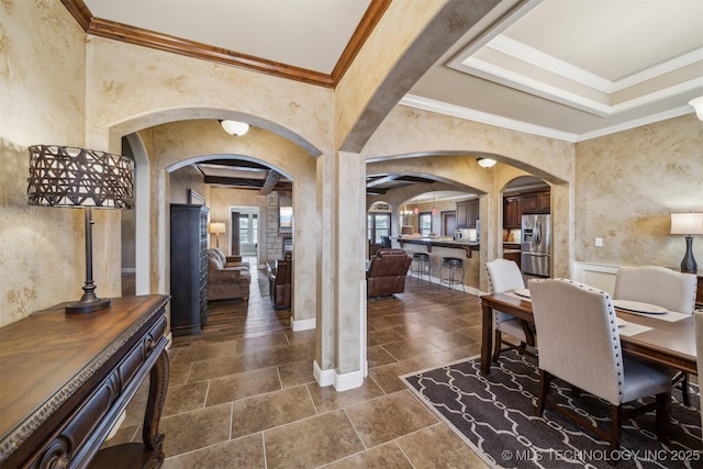 dining area featuring baseboards, arched walkways, and crown molding