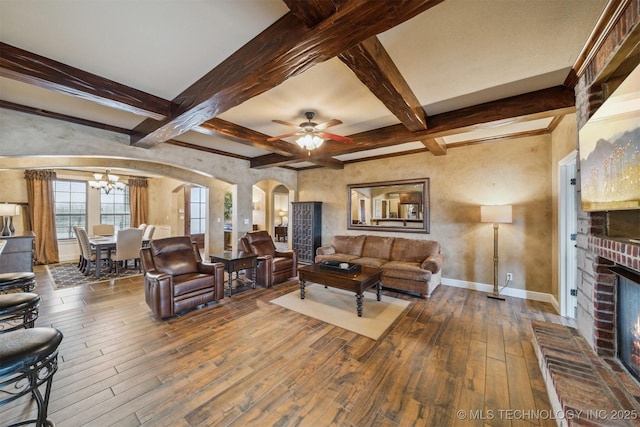 living room featuring a brick fireplace, baseboards, beam ceiling, arched walkways, and wood-type flooring