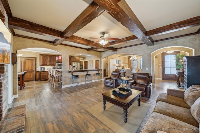 living area with baseboards, beam ceiling, arched walkways, ceiling fan with notable chandelier, and light wood-type flooring