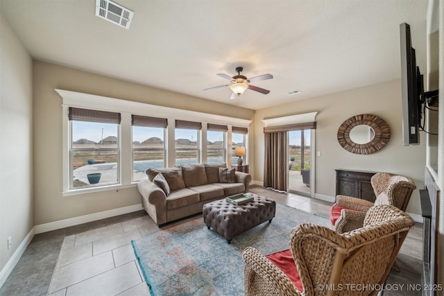 tiled living room featuring visible vents, plenty of natural light, baseboards, and a ceiling fan