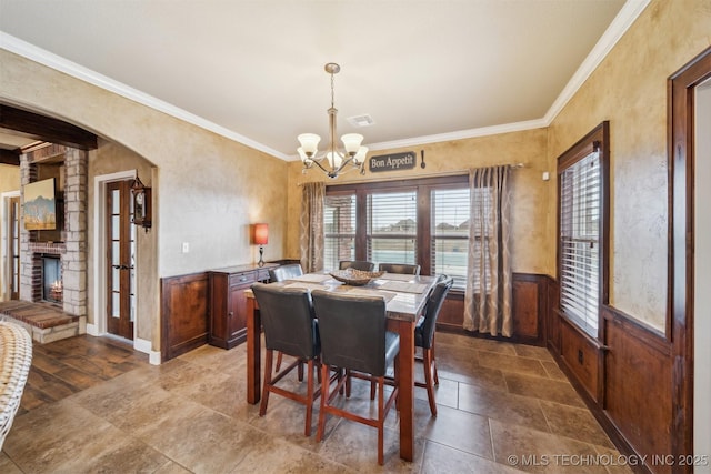 dining space featuring visible vents, a wainscoted wall, arched walkways, ornamental molding, and a notable chandelier