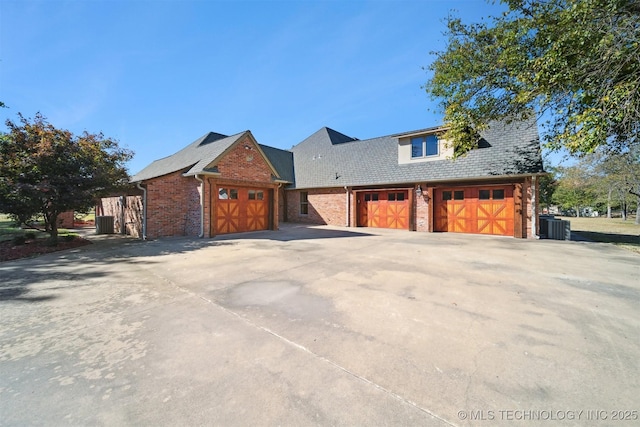 2365 Deer Run, Chouteau, OK 74337 - view of property exterior with brick siding, a garage, cooling unit, and driveway
