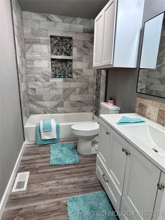 bathroom featuring vanity, wood finished floors, visible vents, shower / tub combination, and toilet