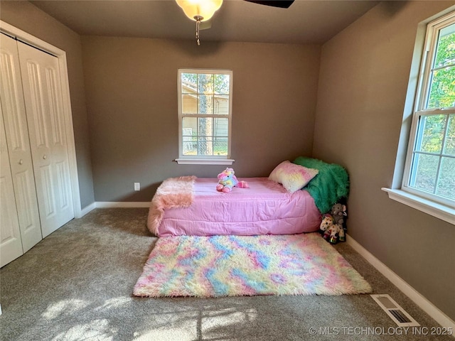 carpeted bedroom with a ceiling fan, baseboards, visible vents, and a closet